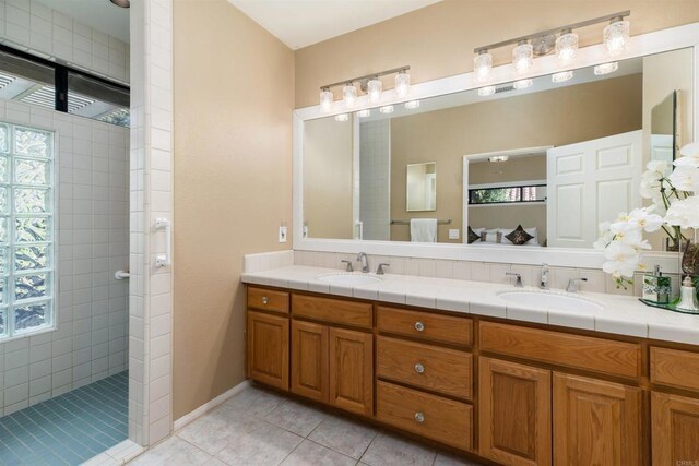 bathroom featuring tile patterned floors, vanity, and a tile shower