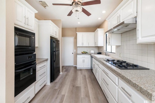 kitchen featuring white cabinetry, sink, light hardwood / wood-style floors, and black appliances