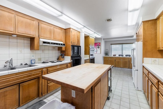 kitchen featuring tile countertops, a kitchen island, sink, white appliances, and tasteful backsplash