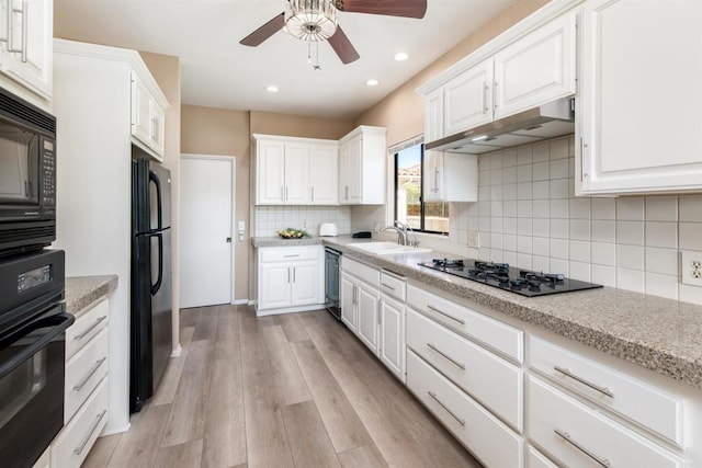 kitchen featuring tasteful backsplash, white cabinets, black appliances, light hardwood / wood-style floors, and sink