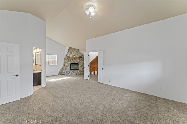 unfurnished living room with vaulted ceiling, light colored carpet, and a stone fireplace