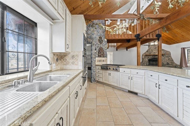 kitchen with tasteful backsplash, sink, white cabinetry, light stone countertops, and wooden ceiling