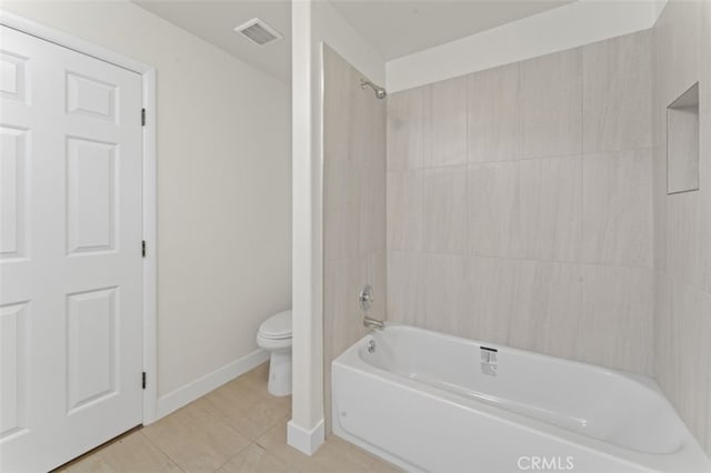 bathroom featuring toilet, tiled shower / bath, and tile patterned floors