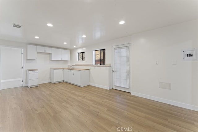 kitchen featuring kitchen peninsula, white cabinetry, light hardwood / wood-style flooring, and sink