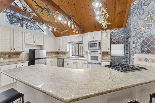 kitchen featuring a kitchen breakfast bar, stainless steel appliances, kitchen peninsula, and high vaulted ceiling