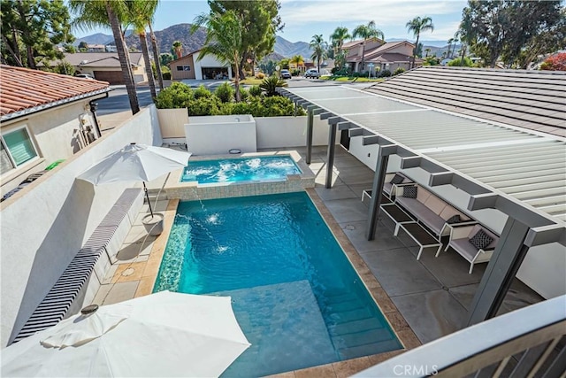 view of swimming pool with pool water feature, a mountain view, a patio area, and an in ground hot tub