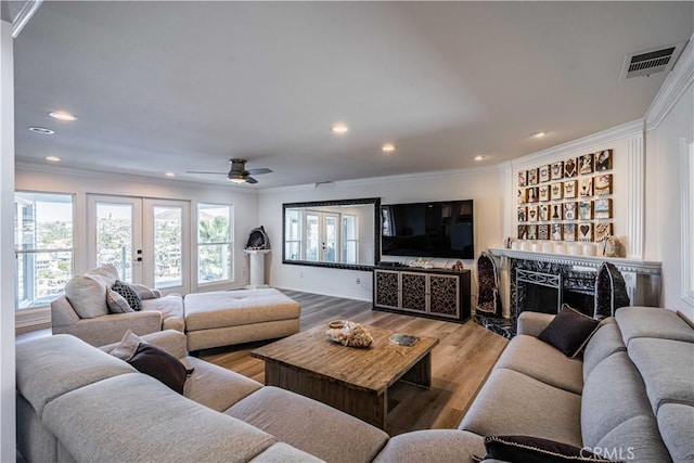 living room with ceiling fan, wood-type flooring, ornamental molding, and french doors