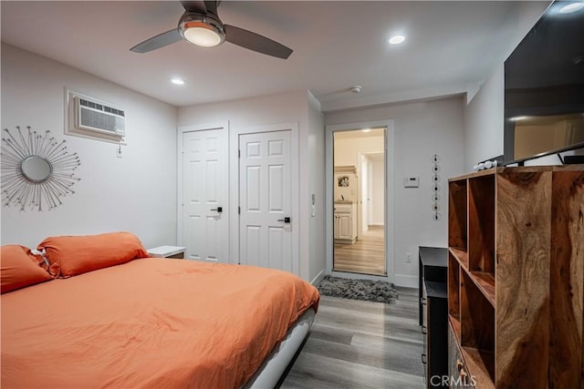 bedroom with a wall mounted AC, dark hardwood / wood-style floors, and ceiling fan