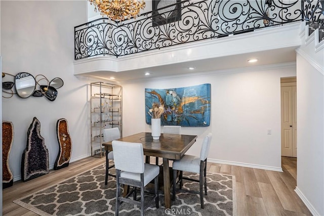 dining room featuring a high ceiling, hardwood / wood-style flooring, crown molding, and a notable chandelier