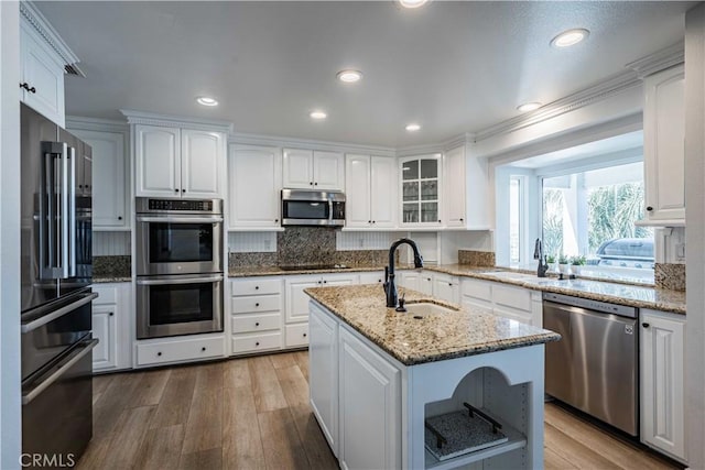 kitchen with a kitchen island with sink, sink, white cabinets, and appliances with stainless steel finishes