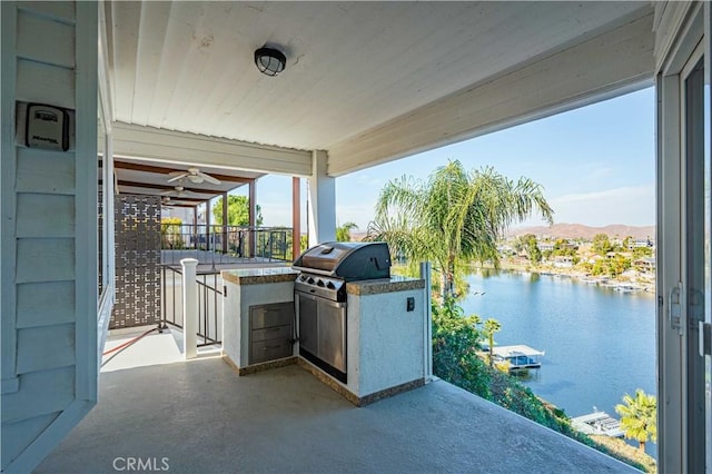 view of patio with grilling area, a water and mountain view, and exterior kitchen