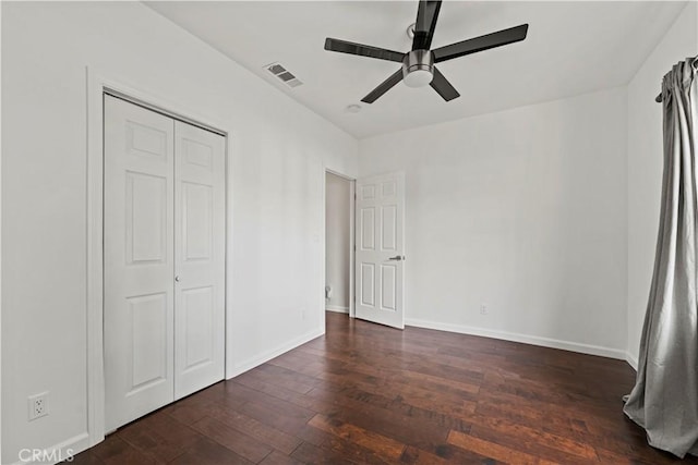 unfurnished bedroom with ceiling fan, a closet, and dark wood-type flooring