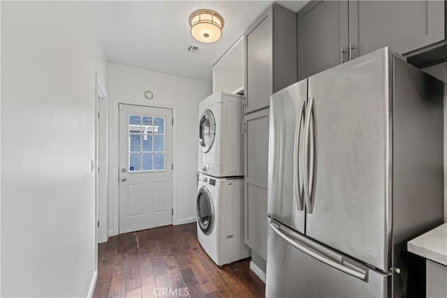 laundry area featuring stacked washer / drying machine and dark hardwood / wood-style floors