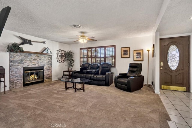 tiled living room featuring ceiling fan, a fireplace, and a textured ceiling