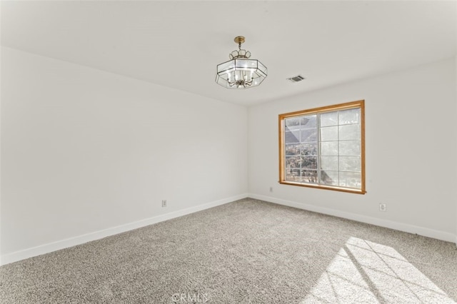 carpeted spare room featuring a notable chandelier