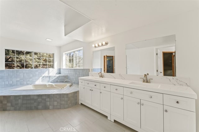 bathroom with a relaxing tiled tub, tile patterned floors, and vanity