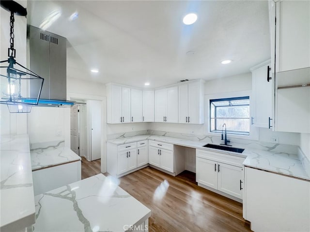 kitchen featuring light stone counters, sink, pendant lighting, and white cabinets