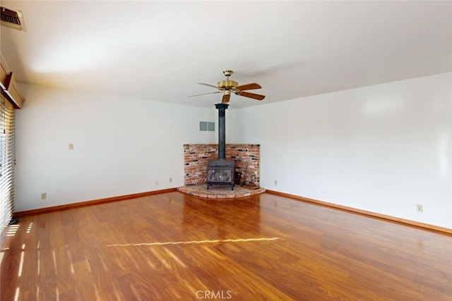 unfurnished living room with a wood stove, ceiling fan, and hardwood / wood-style flooring