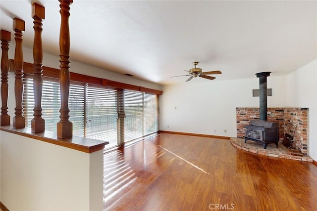 unfurnished living room with hardwood / wood-style floors, a wood stove, and ceiling fan