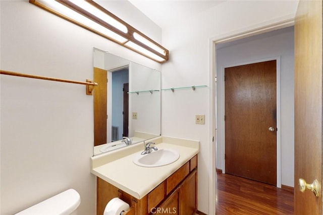 bathroom with toilet, vanity, and hardwood / wood-style flooring