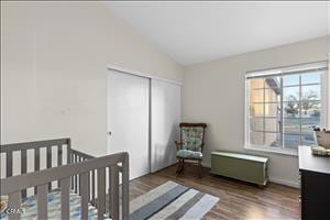 bedroom featuring a crib, dark hardwood / wood-style flooring, lofted ceiling, and a closet