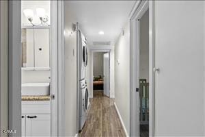 hallway featuring wood-type flooring and stacked washer / drying machine