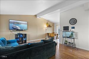 living room featuring vaulted ceiling with beams and hardwood / wood-style floors