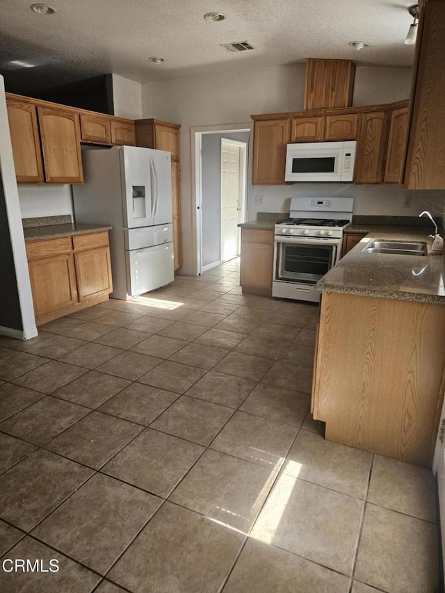 kitchen with a textured ceiling, white appliances, tile patterned floors, and sink