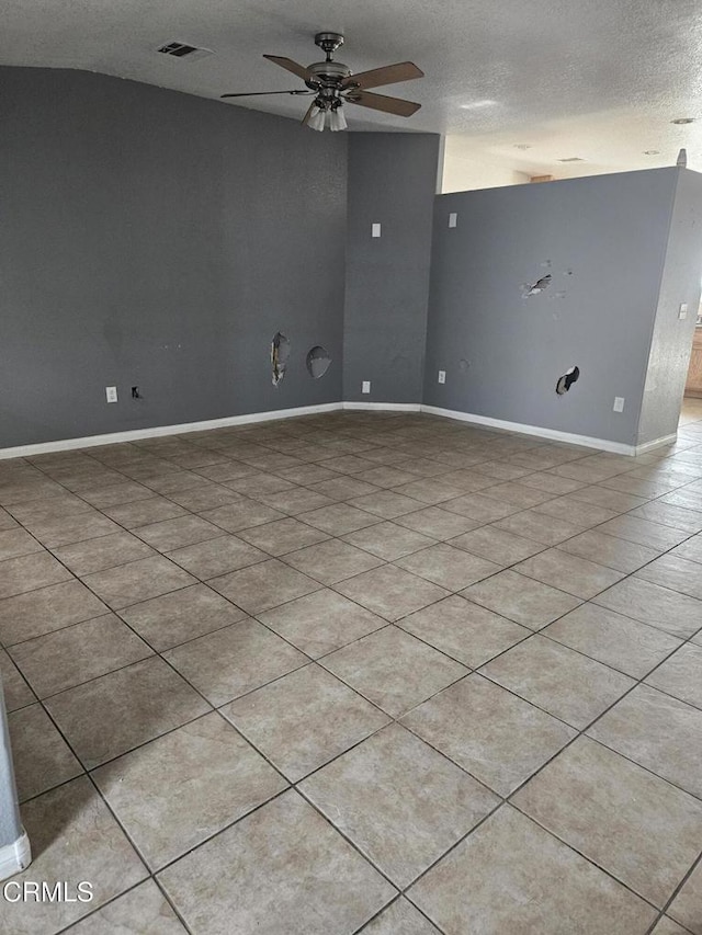 tiled spare room with ceiling fan, a textured ceiling, and vaulted ceiling