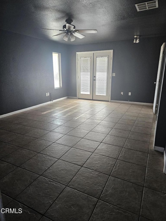 tiled spare room featuring ceiling fan, french doors, and a textured ceiling