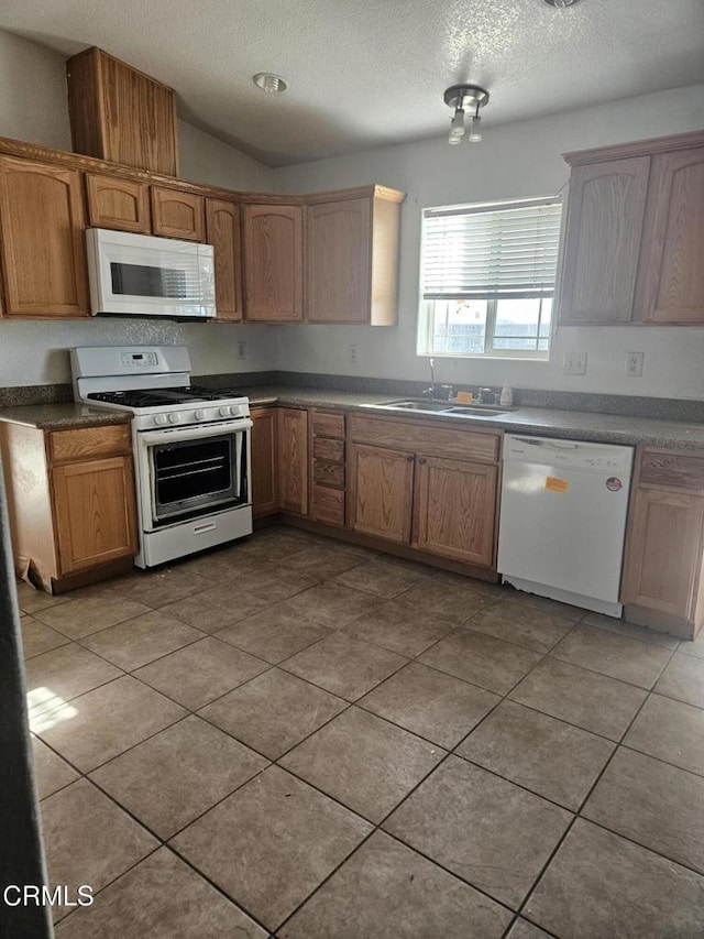 kitchen with lofted ceiling, white appliances, sink, a textured ceiling, and light tile patterned flooring