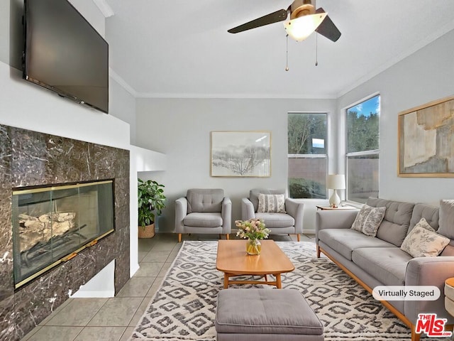 living room featuring ceiling fan, light tile patterned flooring, crown molding, and a tile fireplace