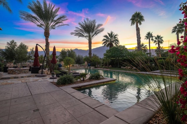 pool at dusk featuring a mountain view and a patio