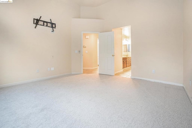 empty room featuring light colored carpet and a high ceiling