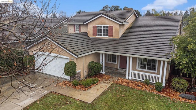 view of front of property featuring a garage, a front lawn, and covered porch