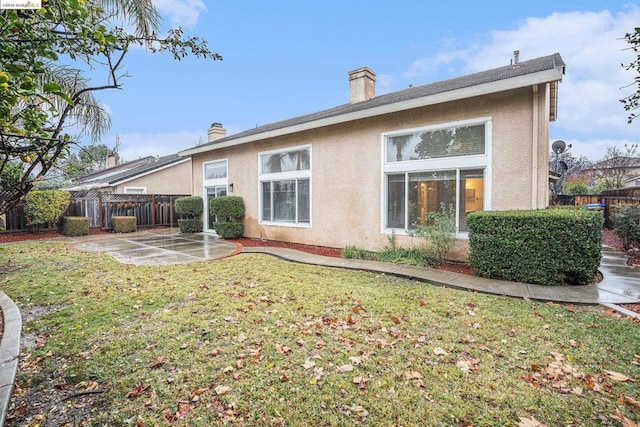 rear view of house with a lawn and a patio