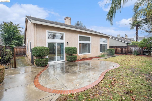 back of house with a patio area and a lawn