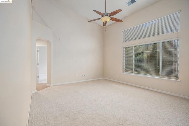 empty room featuring ceiling fan, a towering ceiling, and light carpet