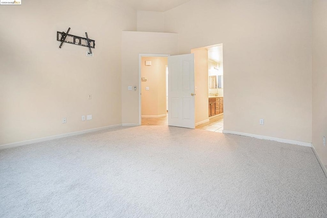 carpeted spare room with a towering ceiling