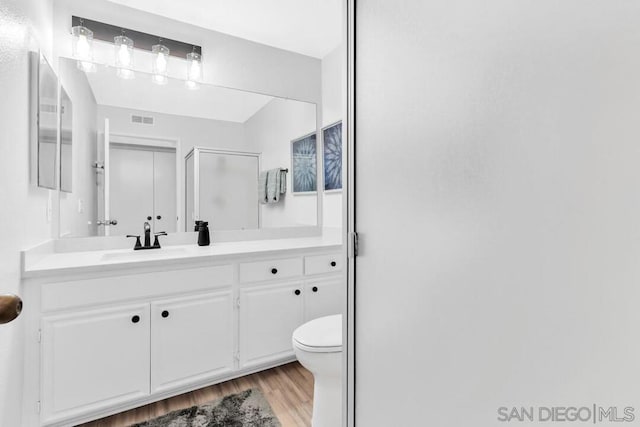 bathroom featuring hardwood / wood-style floors, vanity, toilet, and a shower with shower door