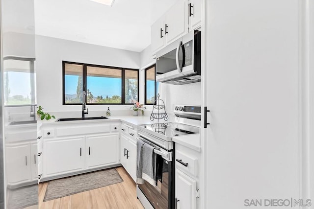 kitchen featuring stainless steel appliances, white cabinetry, and light hardwood / wood-style floors