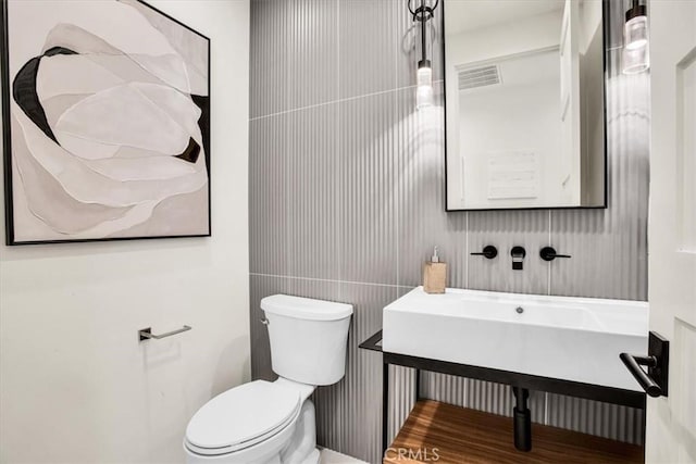 bathroom with toilet and tile walls