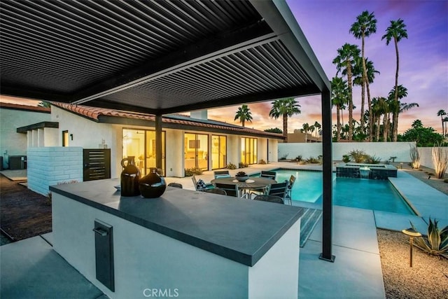 pool at dusk featuring central AC unit, a patio area, an in ground hot tub, and exterior bar