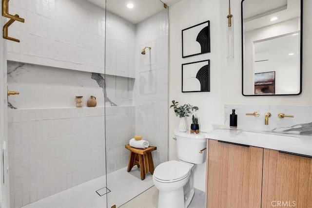 bathroom with vanity, a tile shower, and toilet