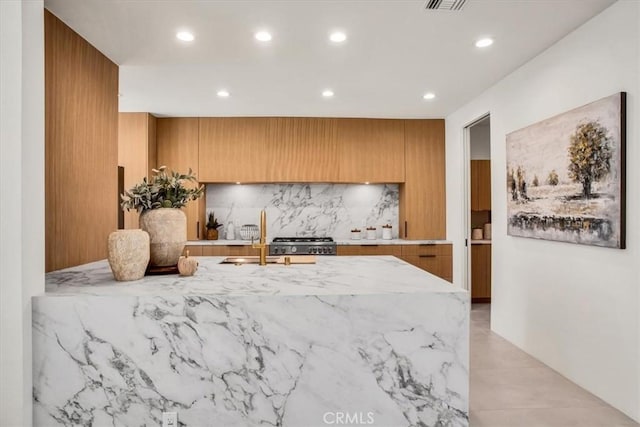 kitchen with tasteful backsplash, range, and sink