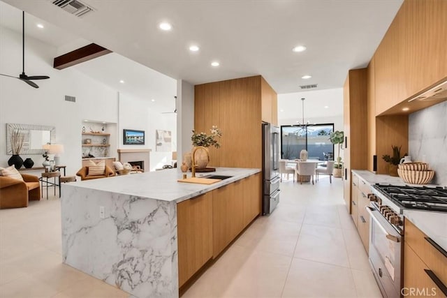 kitchen featuring appliances with stainless steel finishes, ceiling fan with notable chandelier, sink, light tile patterned floors, and light stone countertops