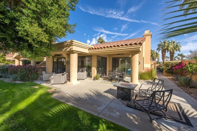 rear view of house with a patio, ceiling fan, an outdoor fire pit, and a lawn