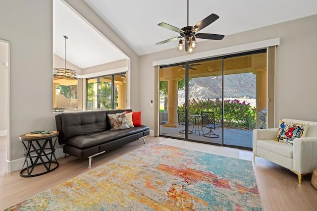 living room with a mountain view, wood-type flooring, vaulted ceiling, and ceiling fan