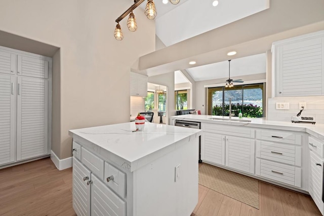 kitchen with white cabinets, a kitchen island, light hardwood / wood-style floors, and sink