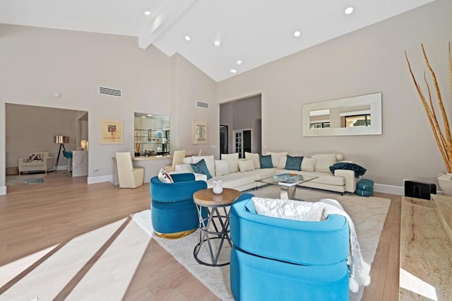 living room featuring light hardwood / wood-style flooring, high vaulted ceiling, and beamed ceiling